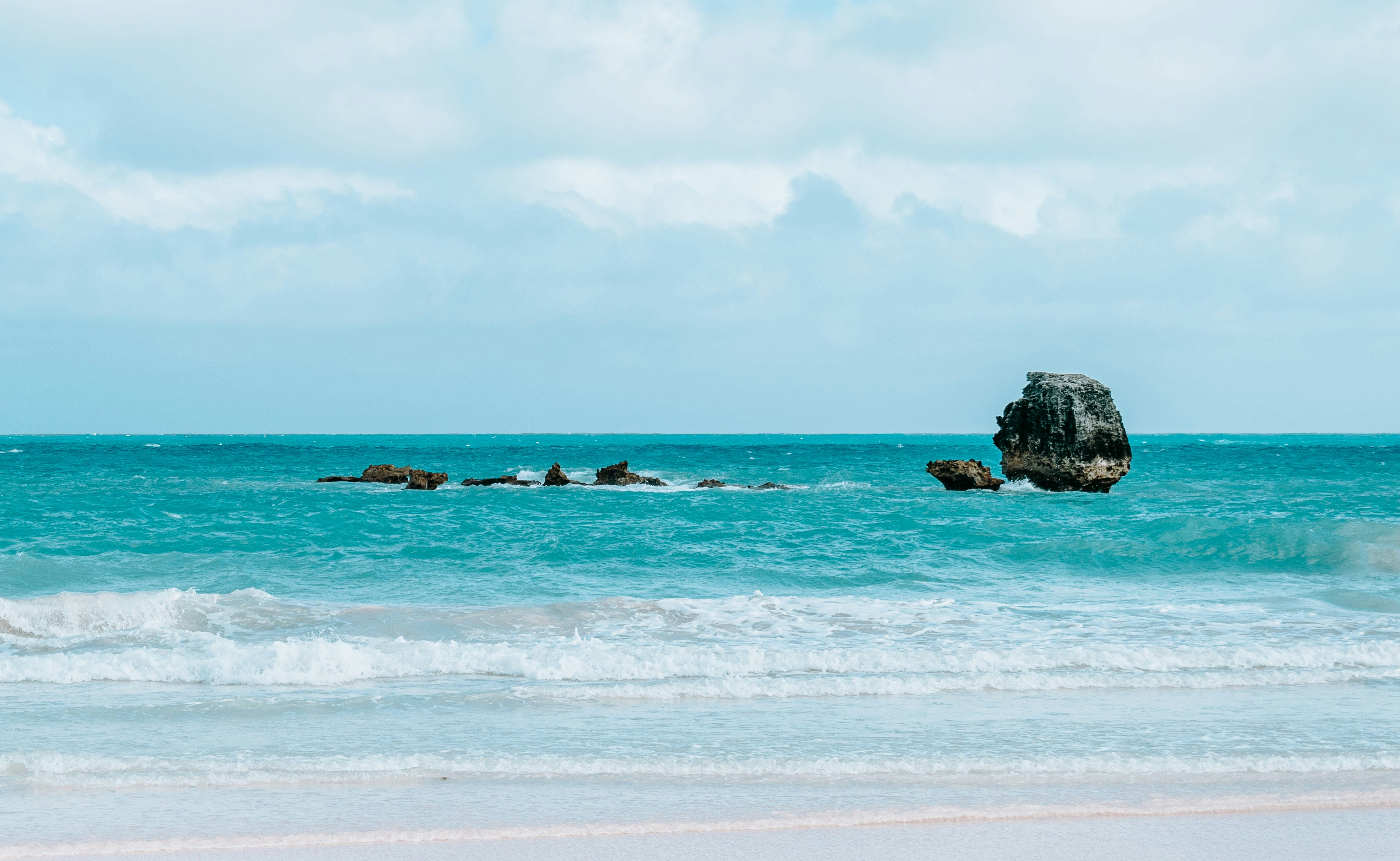 brown rock formation on sea under white clouds during daytime